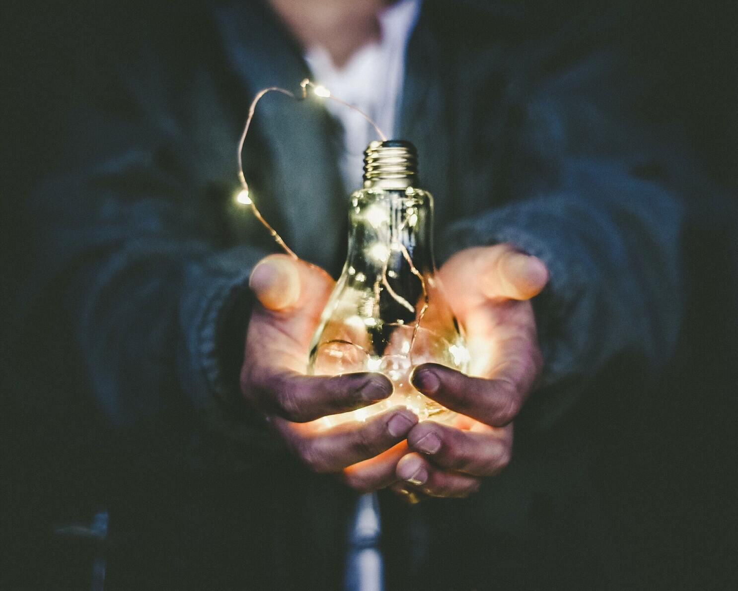 Hands holding lights into a glass recipient