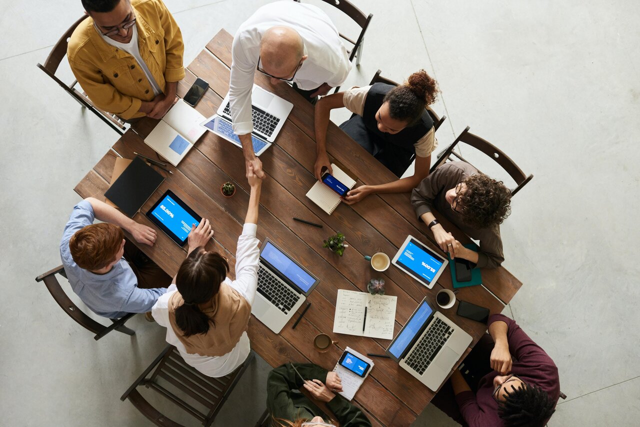 People gathered around a table, two of them are shaking hands