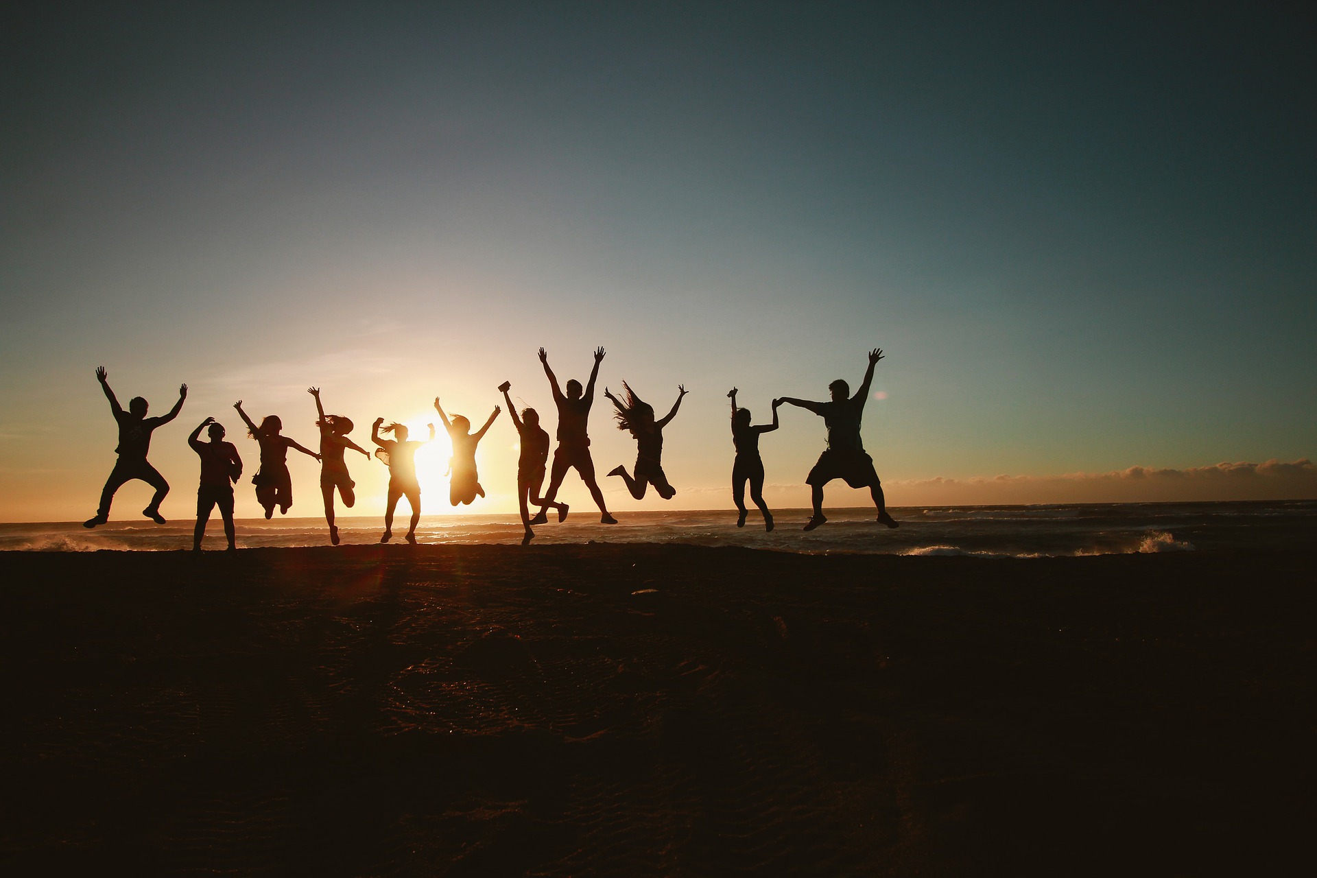 Happy people jumping on a beach during sunset